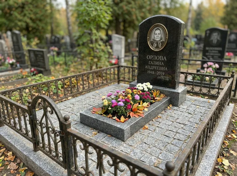 Благоустроенное захоронение с гранитной плиткой, оградой и цветником в Мурманске