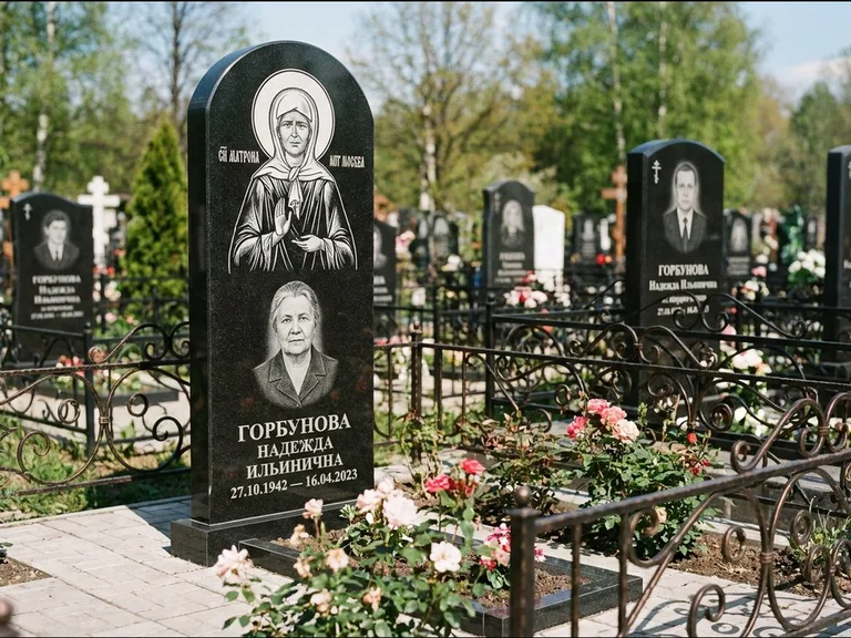 Памятник с гравировкой иконы: стела с арочным верхом и киотом под образ — гравировка образа Матроны Московской, гранитный цоколь с тёмной плиткой, работа «Ковалёв» в Мурманске