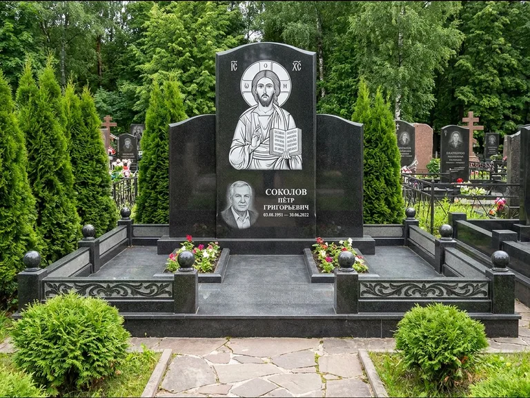 Памятник с гравировкой иконы: широкая горизонтальная лежачая плита-стела — икона в резной рамке-киоте, серая гравийная отсыпка с бордюром, работа «Богданова» в Мурманске