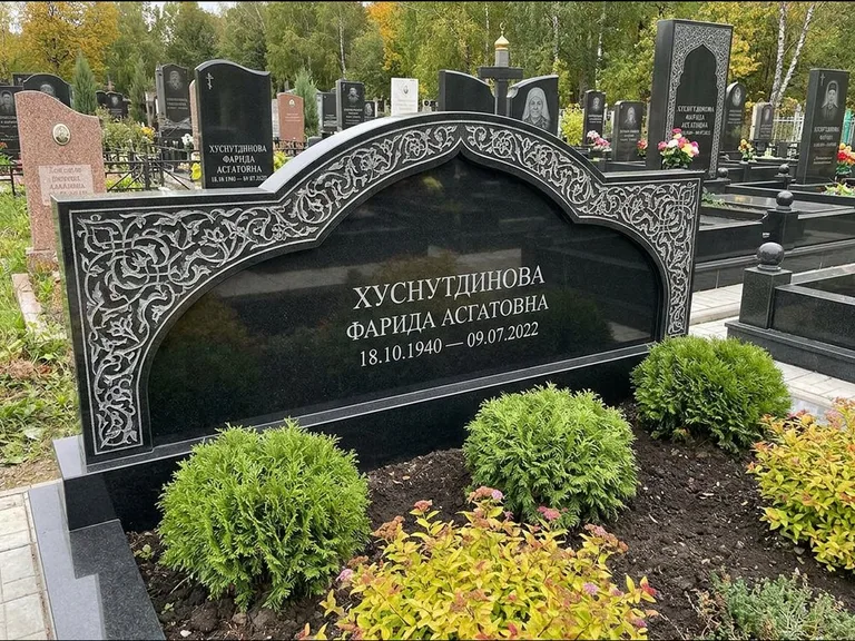 Мусульманский памятник: вытянутая горизонтальная семейная стела с аркой — белая гравировка силуэта мечети с минаретами, участок с декоративными кустами, работа «Зарипова» в Мурманске