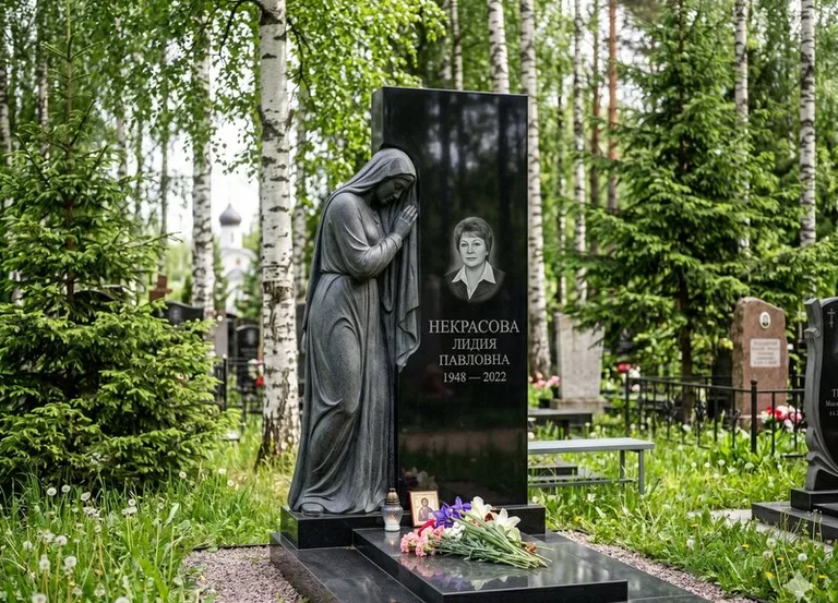 Гранитная фигура скорбящего мужчины у чёрной стелы в Мурманске